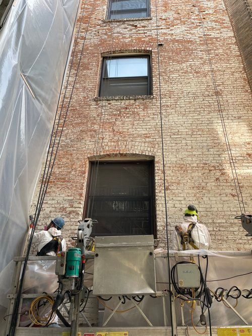 A man is standing on a platform in front of a tall brick building.
