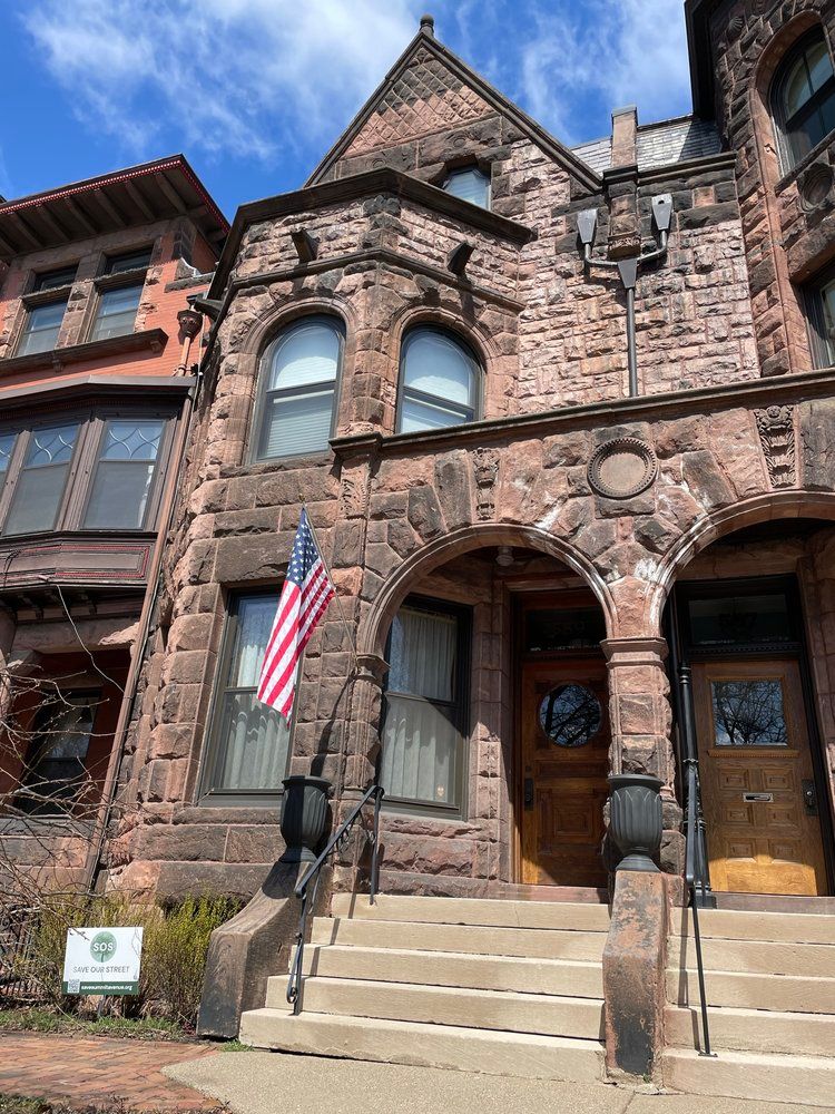 A large brick building with stairs and an american flag on the front.