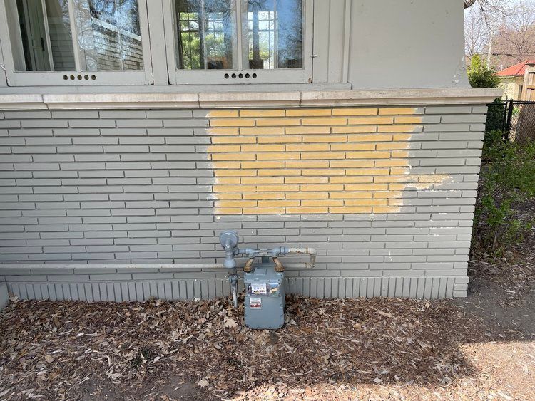 A gas meter is sitting on the side of a brick building.
