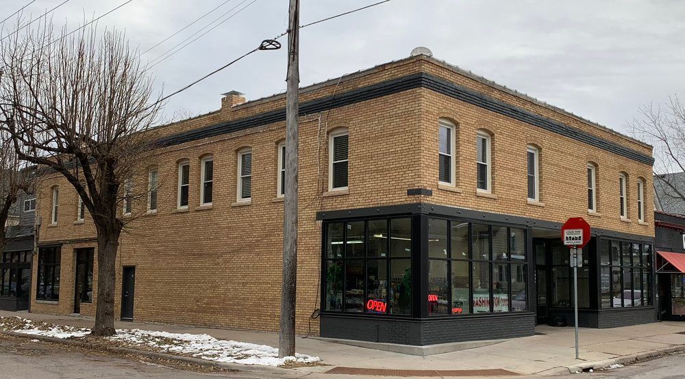A large brick building with a lot of windows is on the corner of a street.