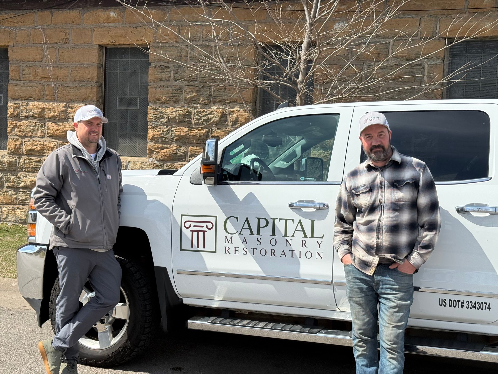 A man wearing a hard hat and safety vest is working on a brick wall