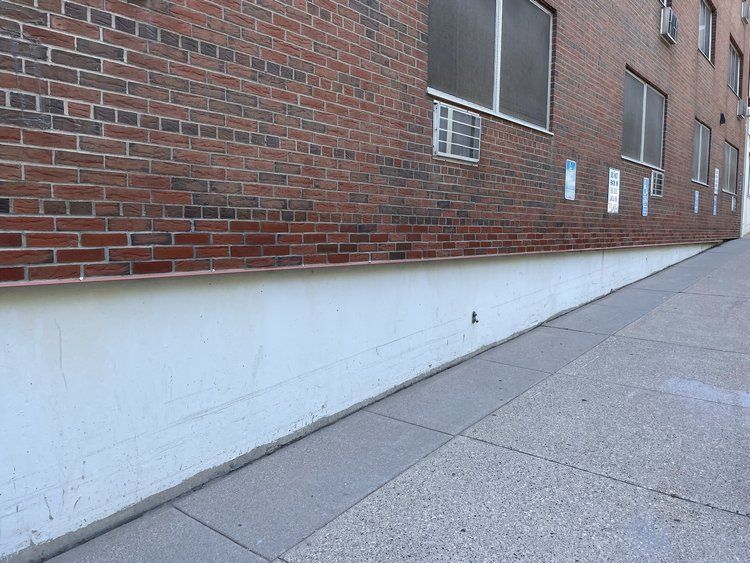 A brick building with a white sidewalk in front of it
