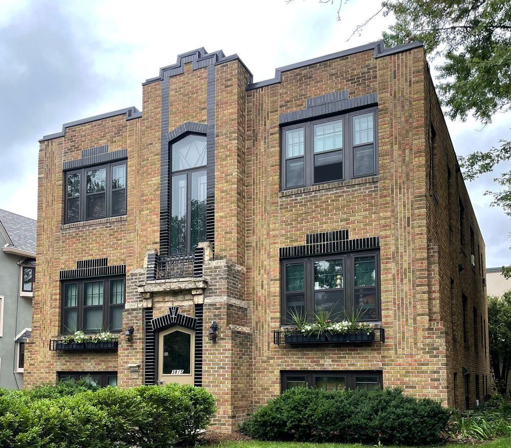 A large brick building with lots of windows and bushes in front of it
