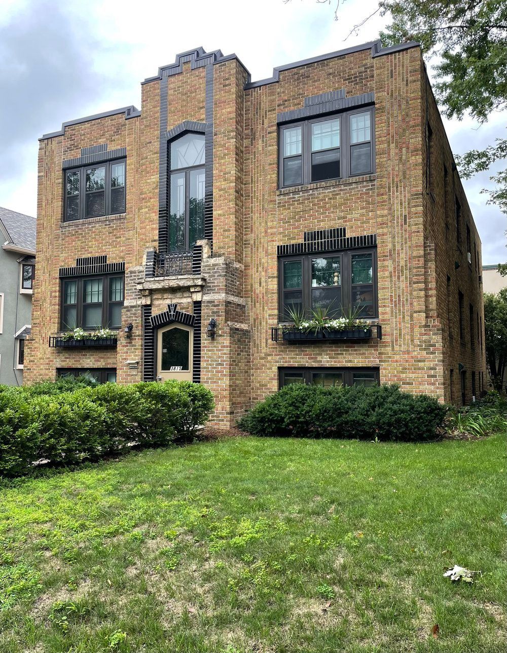 A large brick building with a lot of windows is sitting on top of a lush green lawn.
