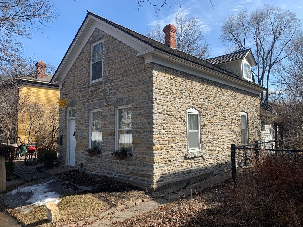 A small stone house with a chimney on the roof.