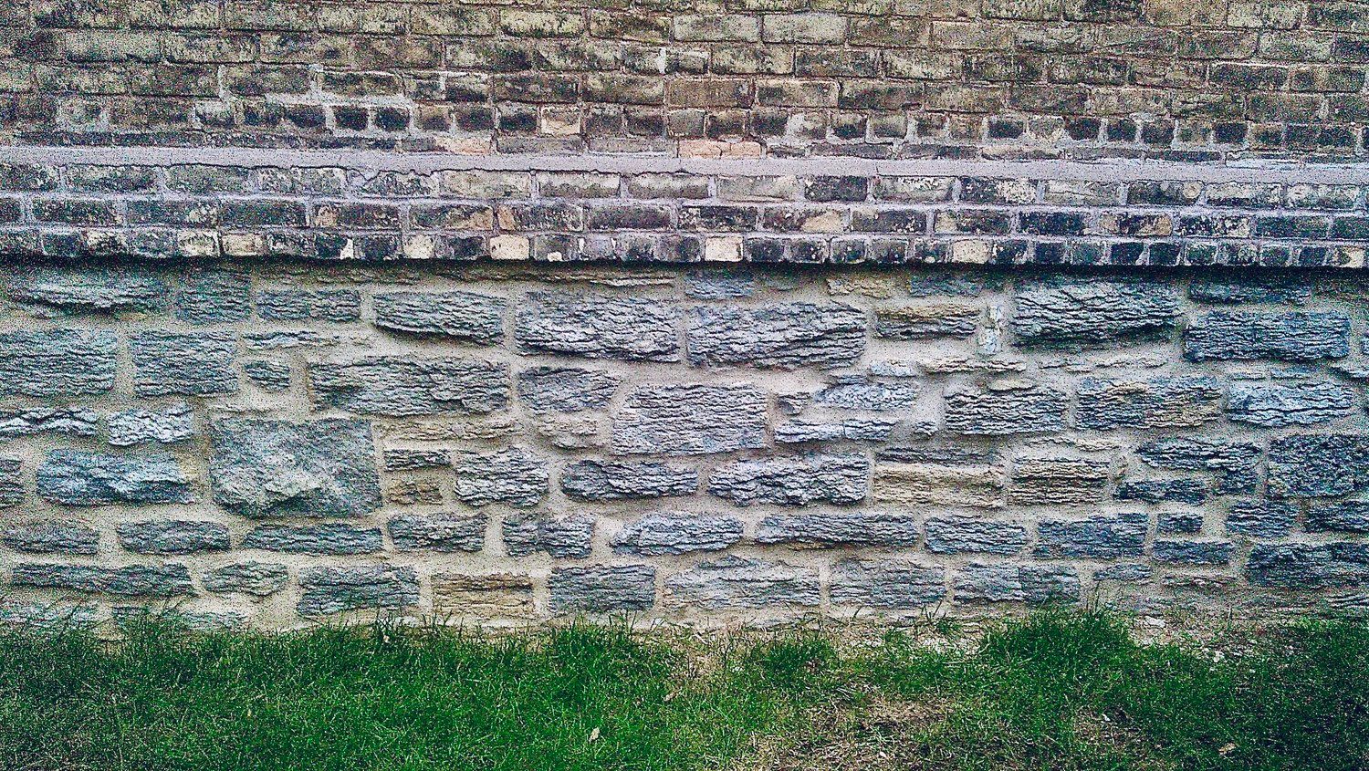A close up of a brick wall with grass in the foreground.