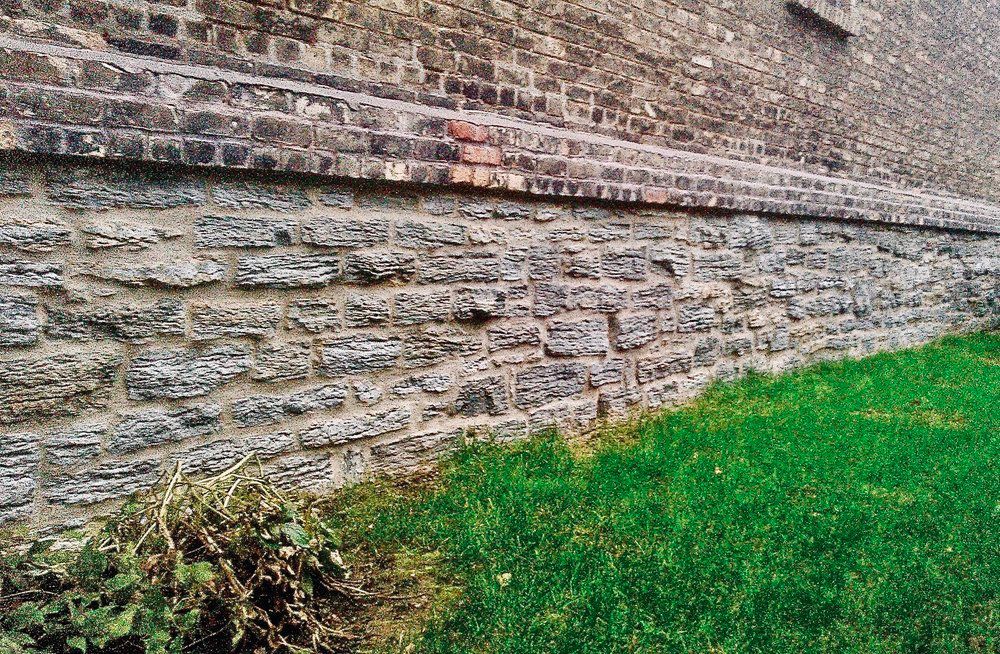 A stone wall with a grassy area in front of it.