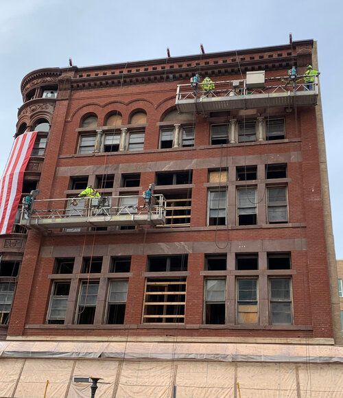 A large brick building under construction with workers on scaffolding