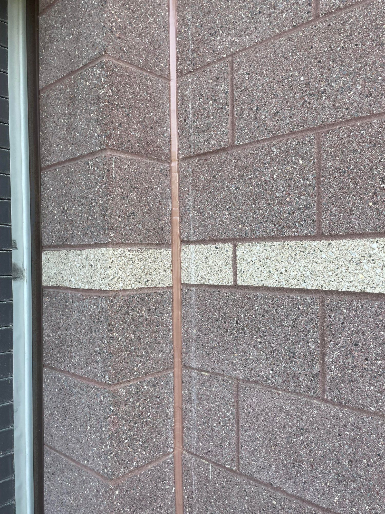 A close up of a brick wall with a copper pipe on it.
