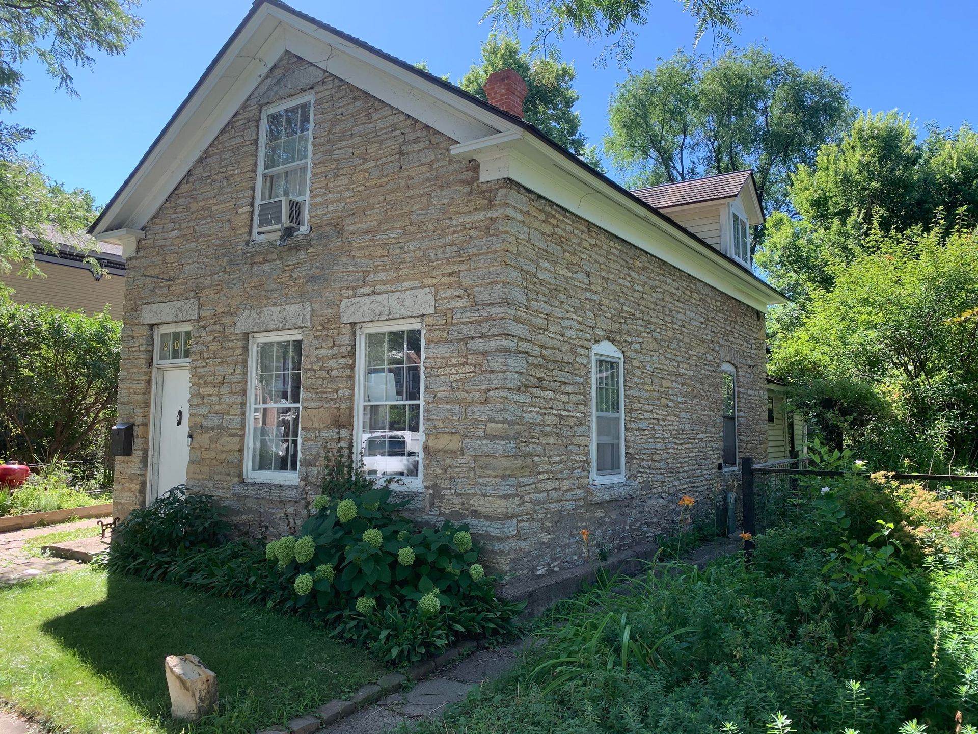 A small stone house with a dog in front of it