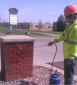 A man wearing a hard hat is spraying brick to seal it