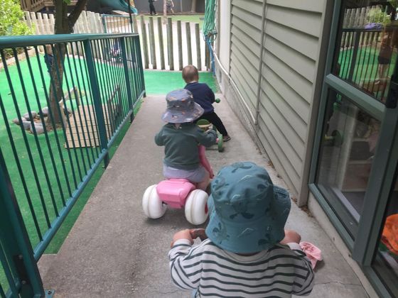 Kids riding trikes at a preschool playground
