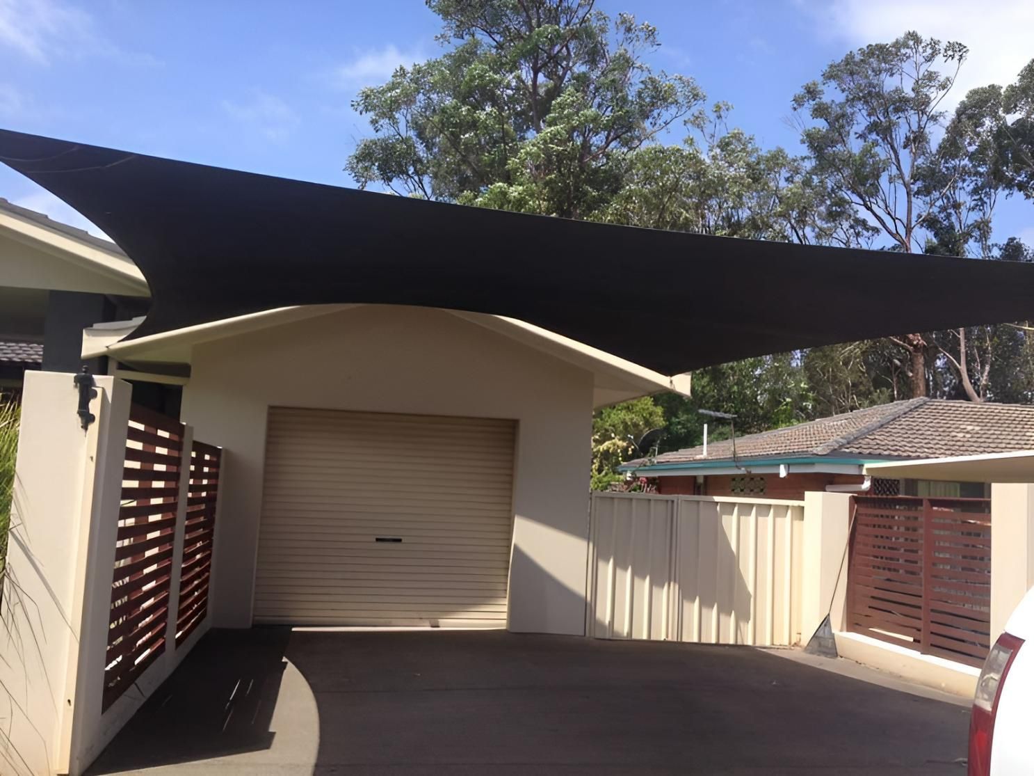 A Car Is Parked Under a Black Canopy in Front of A House — Jon Wilson Canvas & Shade in Coffs Harbour, NSW