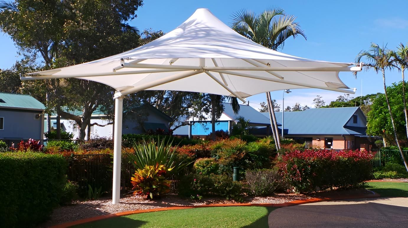 A Large White Umbrella Is in The Middle of A Garden — Jon Wilson Canvas & Shade in Coffs Harbour, NSW