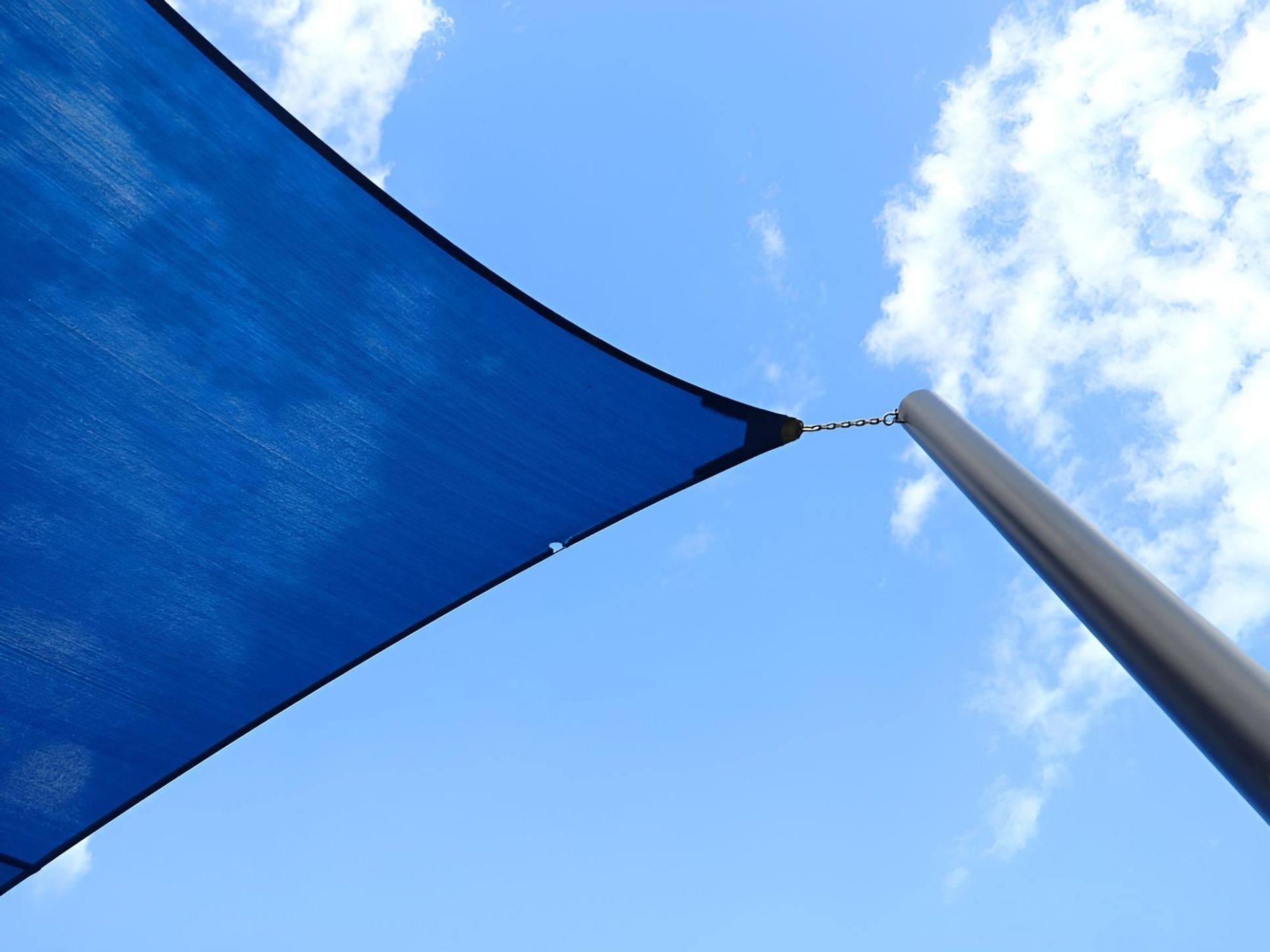 A Blue Umbrella Against a Blue Sky with Clouds — Jon Wilson Canvas & Shade in Coffs Harbour, NSW