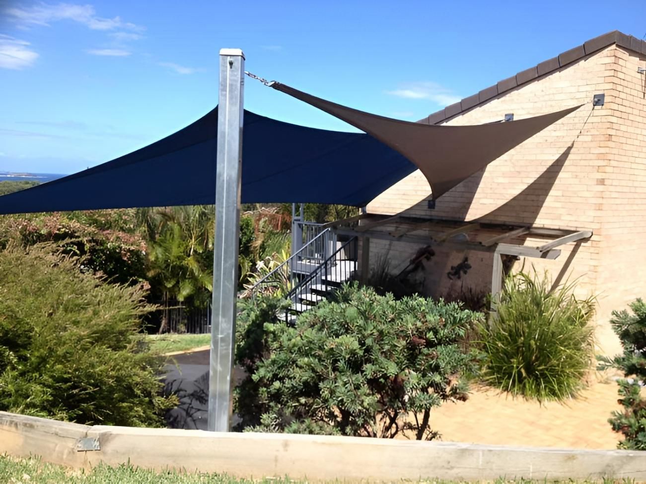 A Large Blue Umbrella Is Sitting in Front of A House — Jon Wilson Canvas & Shade in Nambucca Heads, NSW