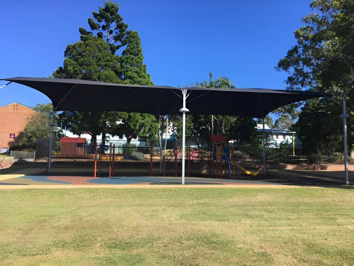 A Large Umbrella Is Covering a Playground in A Park — Jon Wilson Canvas & Shade in Coffs Harbour, NSW