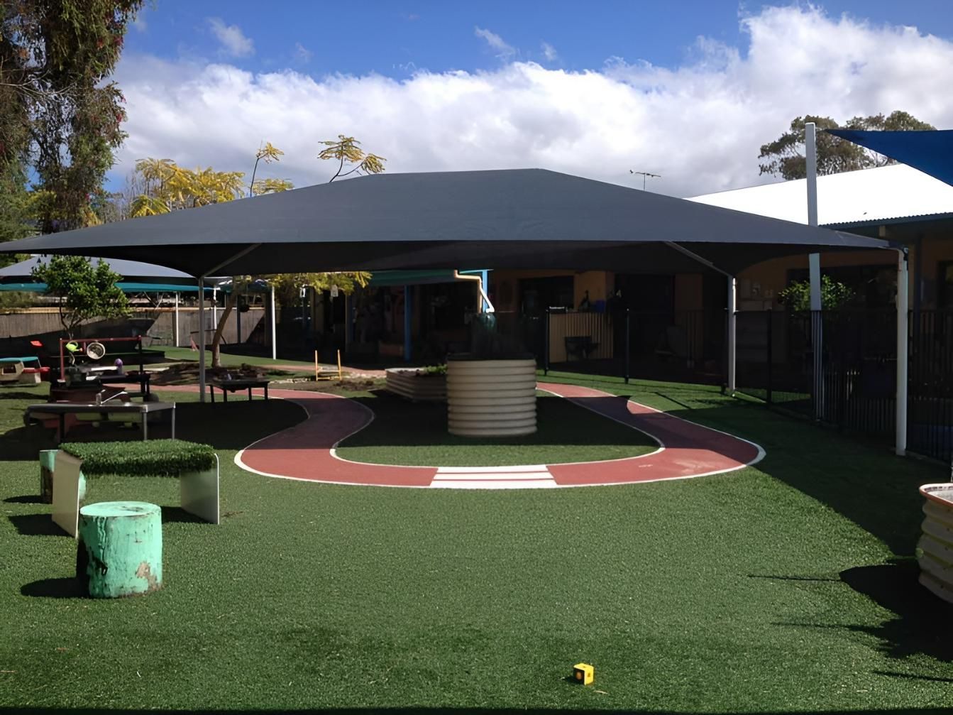 A Large Umbrella Is Sitting on Top of A Lush Green Field — Jon Wilson Canvas & Shade in Coffs Harbour, NSW