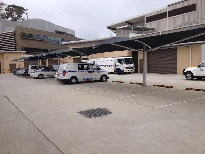 A Row of Cars Are Parked Under Umbrellas in A Parking Lot — Jon Wilson Canvas & Shade in Coffs Harbour, NSW