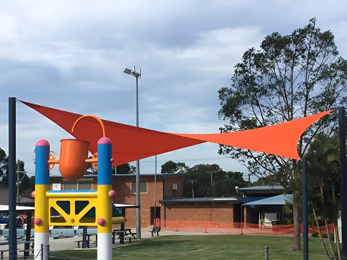 A Colorful Playground with An Orange Triangle Shade Covering It — Jon Wilson Canvas & Shade in Coffs Harbour, NSW