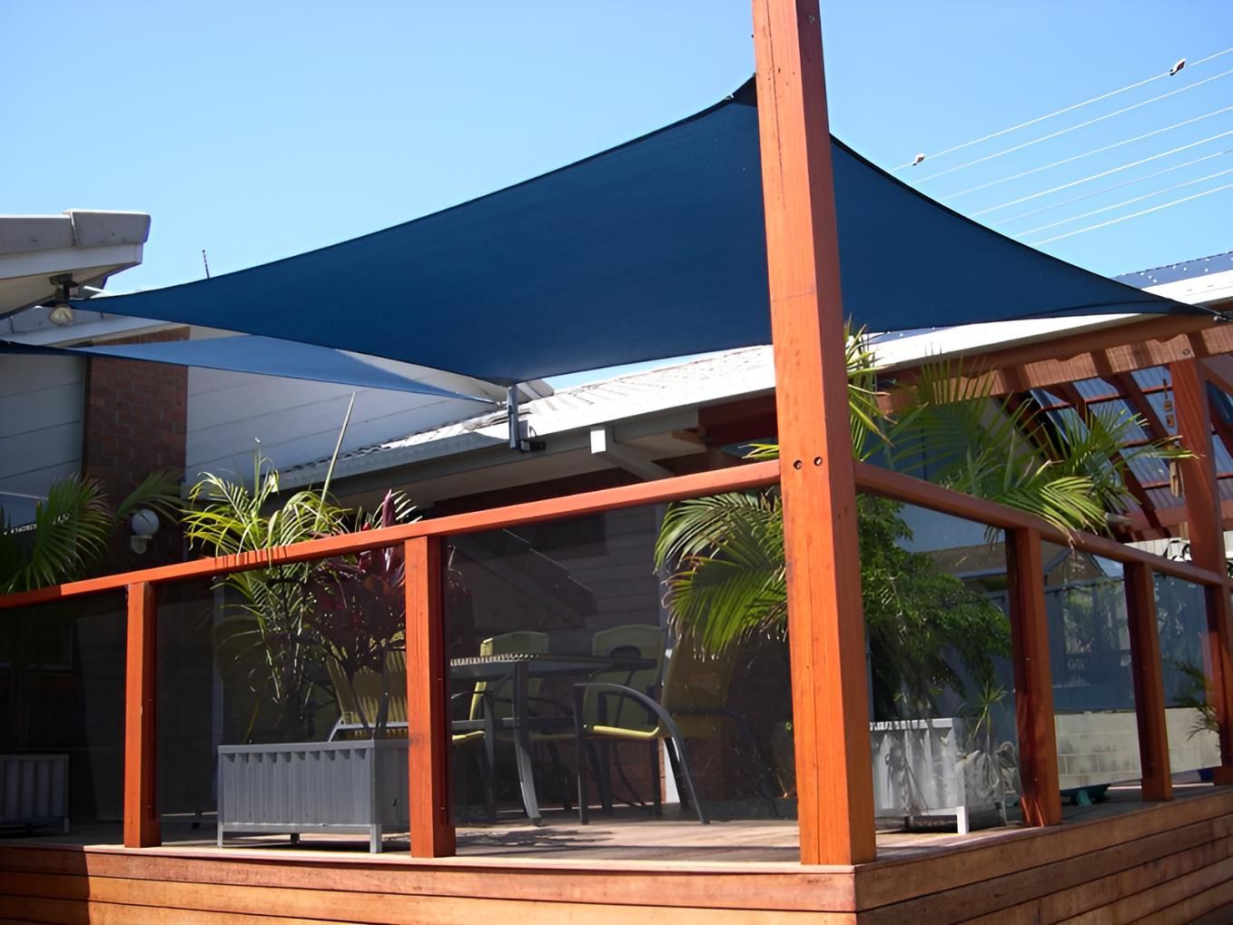 A Wooden Deck with A Blue Umbrella Over It — Jon Wilson Canvas & Shade in Coffs Harbour, NSW