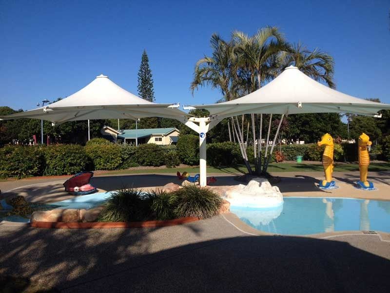 A Swimming Pool with Two Umbrellas and A Statue of A Seahorse — Jon Wilson Canvas & Shade in Coffs Harbour, NSW