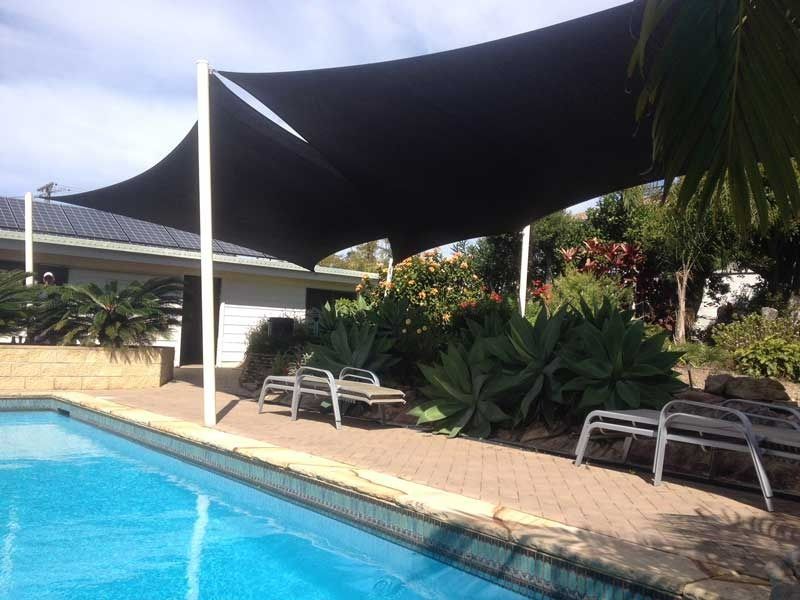 A Large Swimming Pool with A Black Umbrella Over It — Jon Wilson Canvas & Shade in Coffs Harbour, NSW