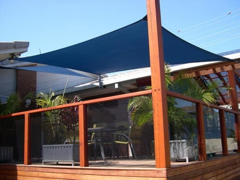 A Wooden Deck with A Blue Umbrella Over It — Jon Wilson Canvas & Shade in Coffs Harbour, NSW