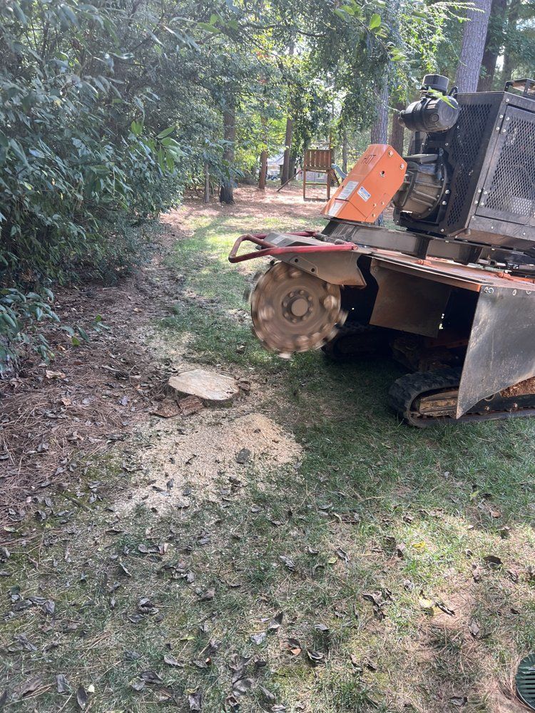 A stump grinder is sitting in the grass next to a tree stump.