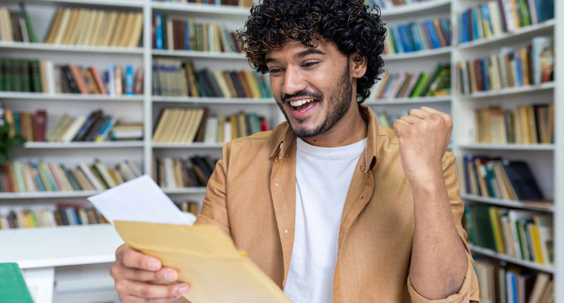 A man is holding a piece of paper in his hand in a library. Building a Strong College Application Po