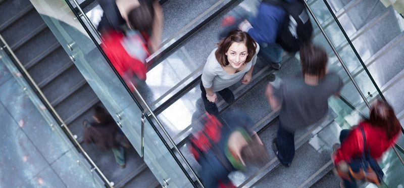 A woman is looking up at the camera while riding an escalator Standing Out at College Fairs