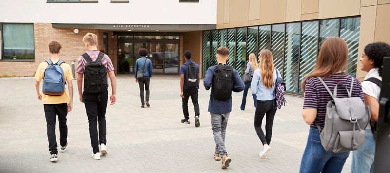 A group of students are walking towards a school building. Navigating College Fairs A Guide for First-Timers