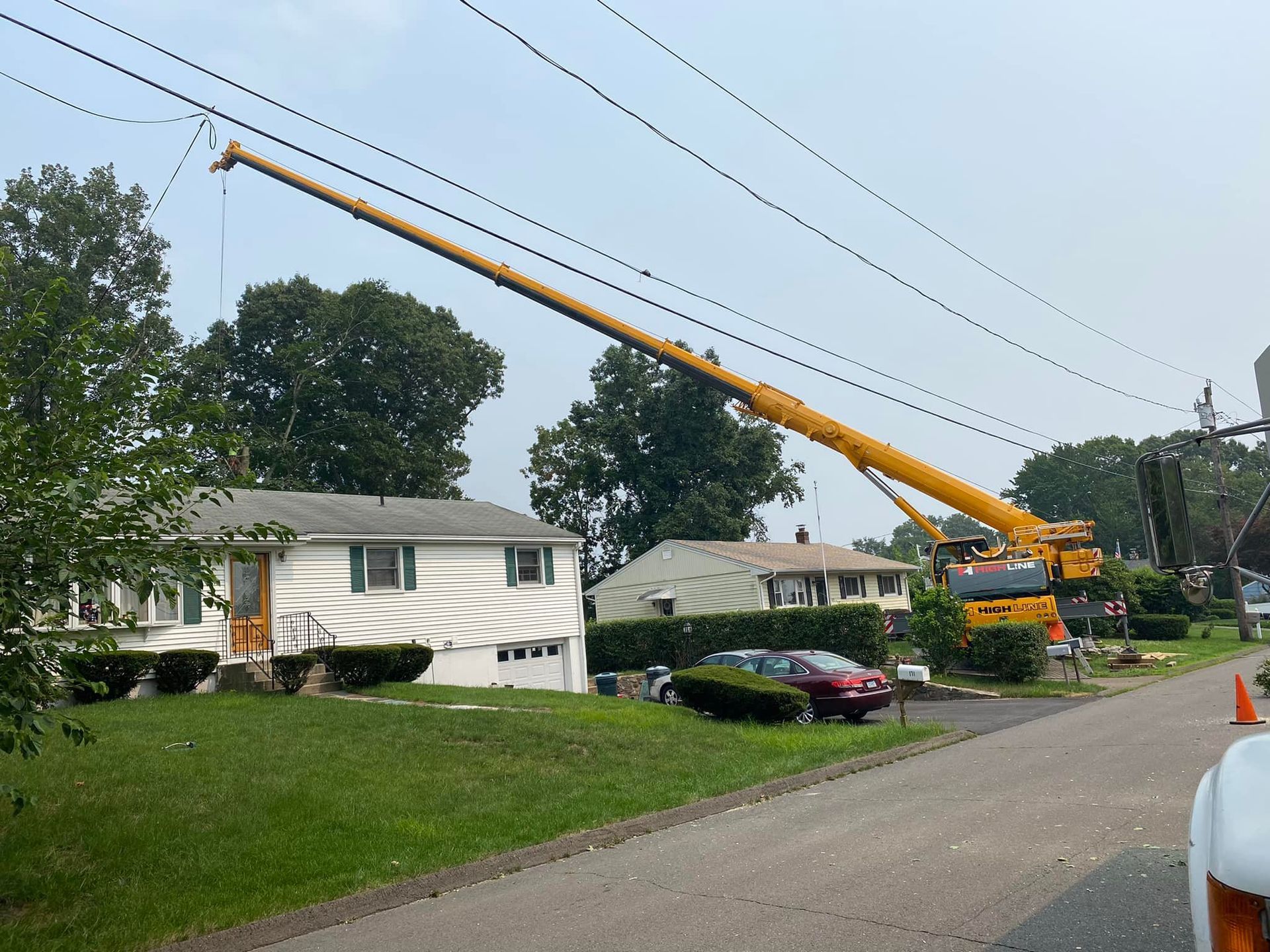 A large yellow crane is working on a house