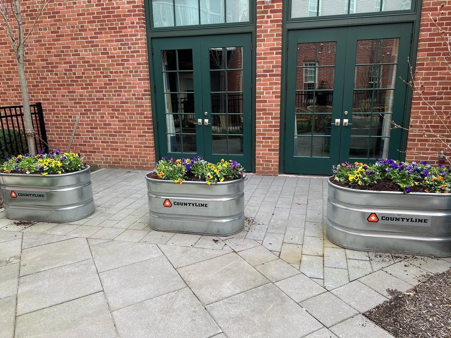 A fence surrounds a lush green hillside with a sign in the background.