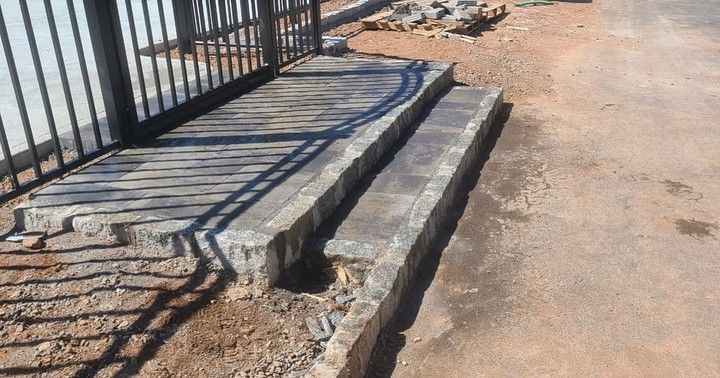 A set of stairs leading up to a fence on a dirt road.