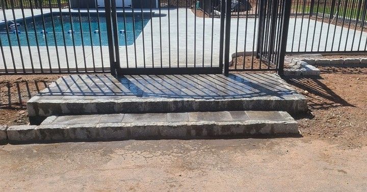 A concrete staircase leading to a pool with a metal fence.