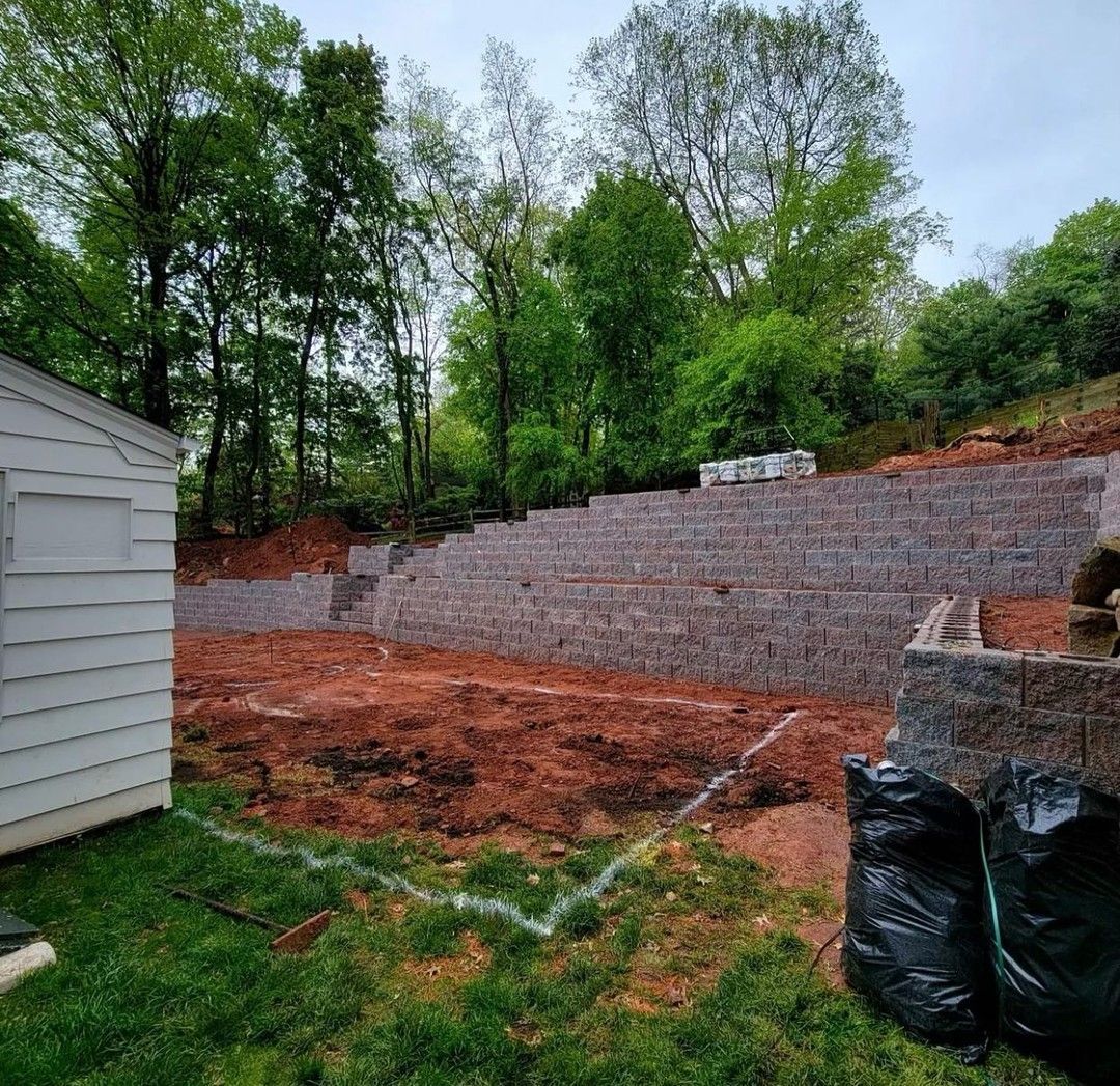 A brick wall is being built in the backyard of a house.