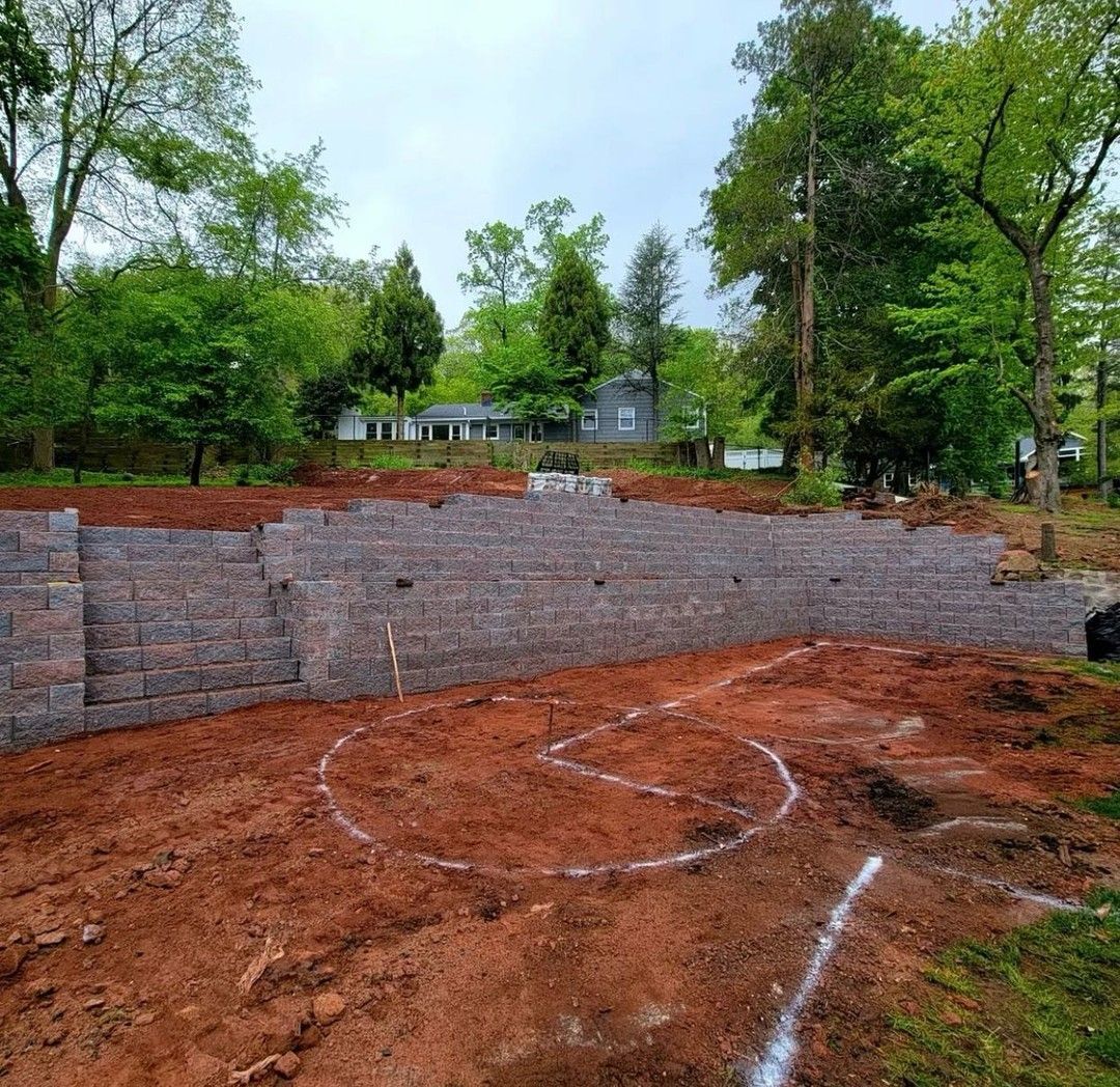 A brick wall is being built in the middle of a dirt field.