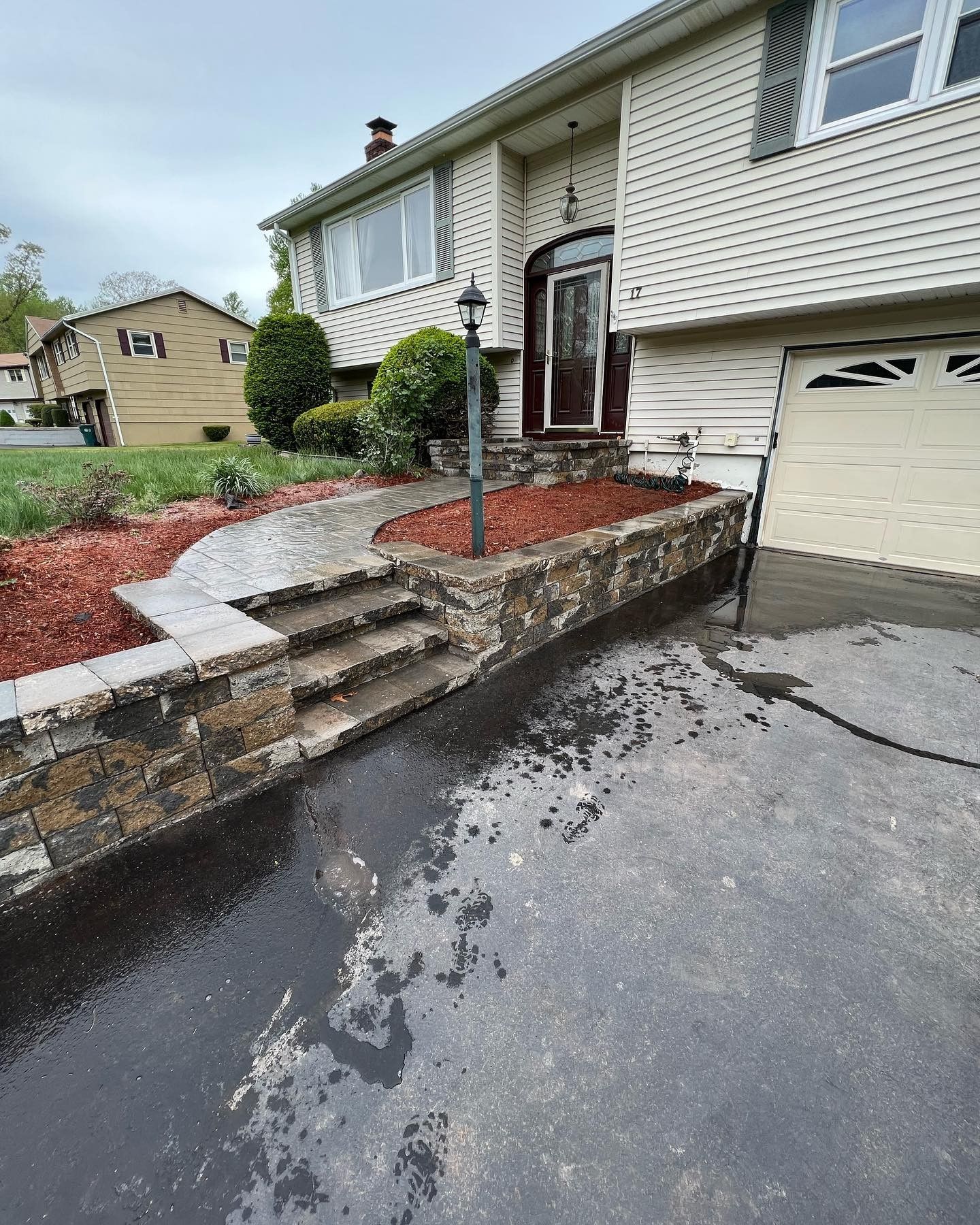 A house with a stone wall and stairs in front of it.