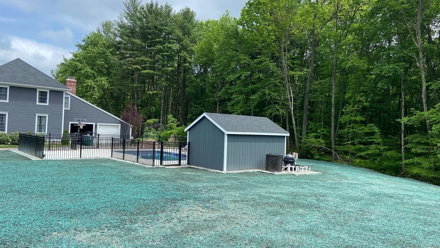 There is a shed in the backyard of a house surrounded by trees.