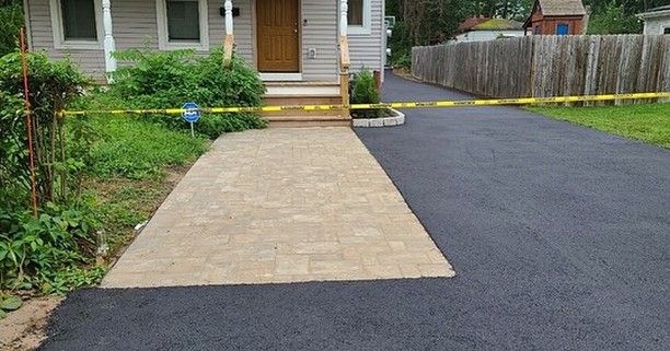 A driveway with a brick walkway leading to a house.