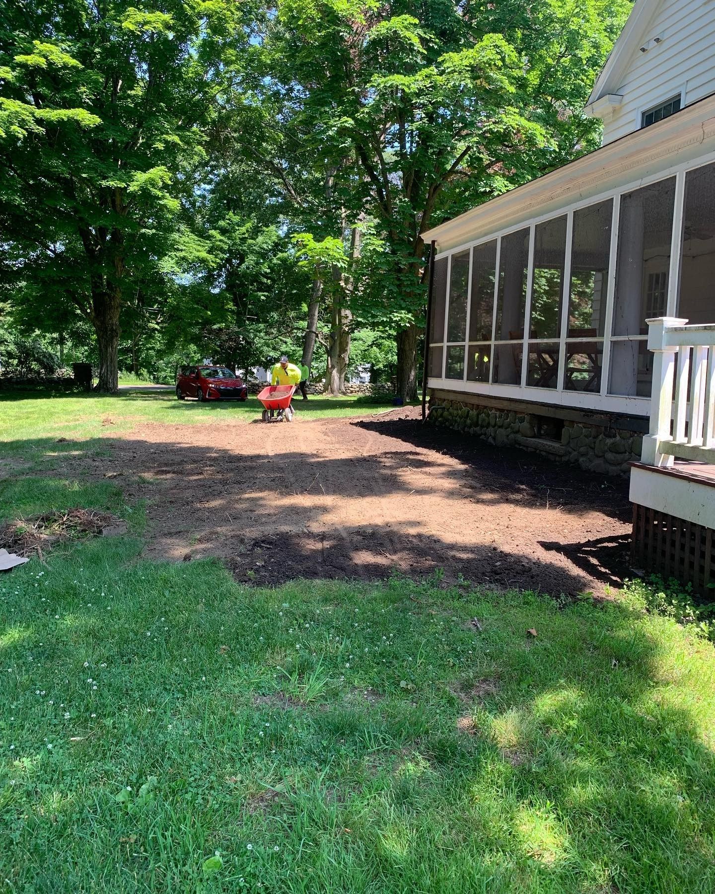 A house with a screened in porch and a wheelbarrow in front of it.