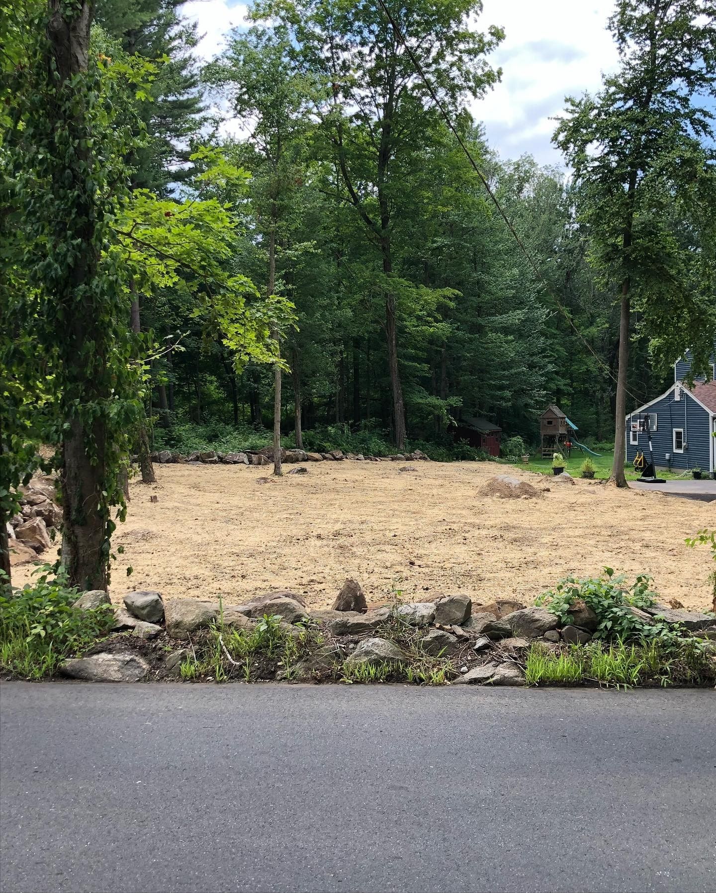 A dirt field with trees and a house in the background.