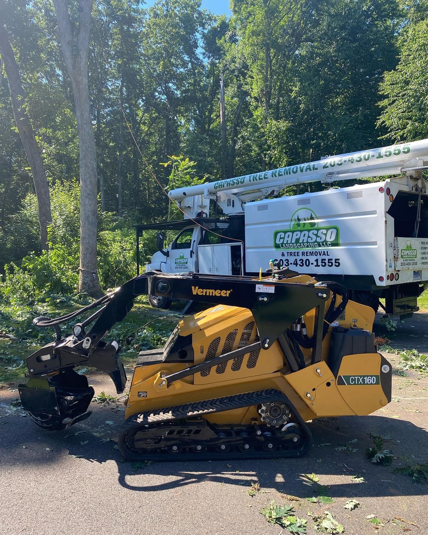 A yellow and black machine is parked next to a white truck.