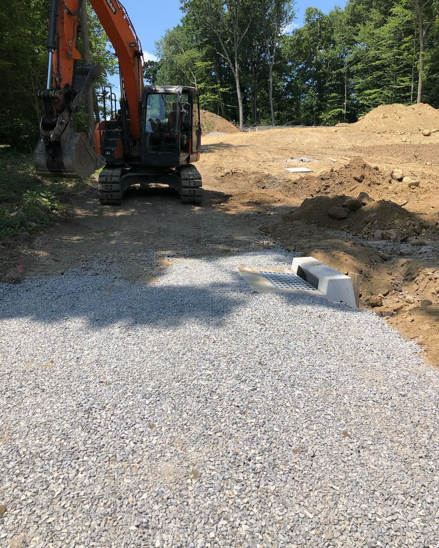 A large orange excavator is sitting on top of a gravel road.