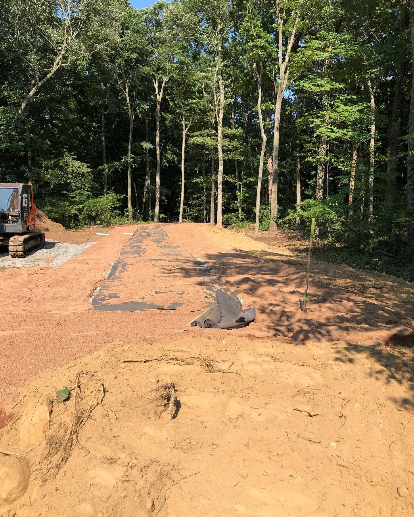 A bulldozer is working on a dirt road in the woods.