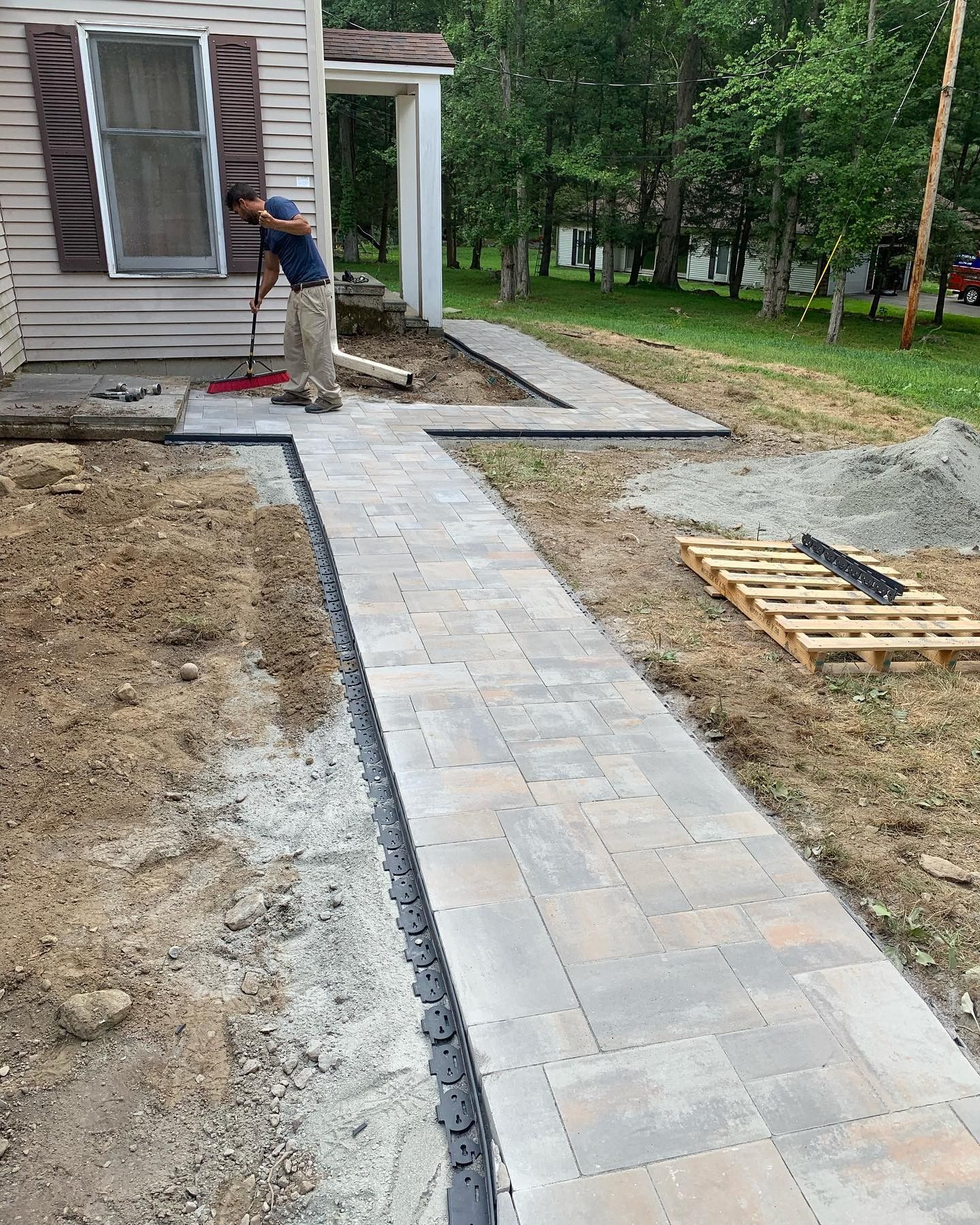 A man is standing on a sidewalk in front of a house.