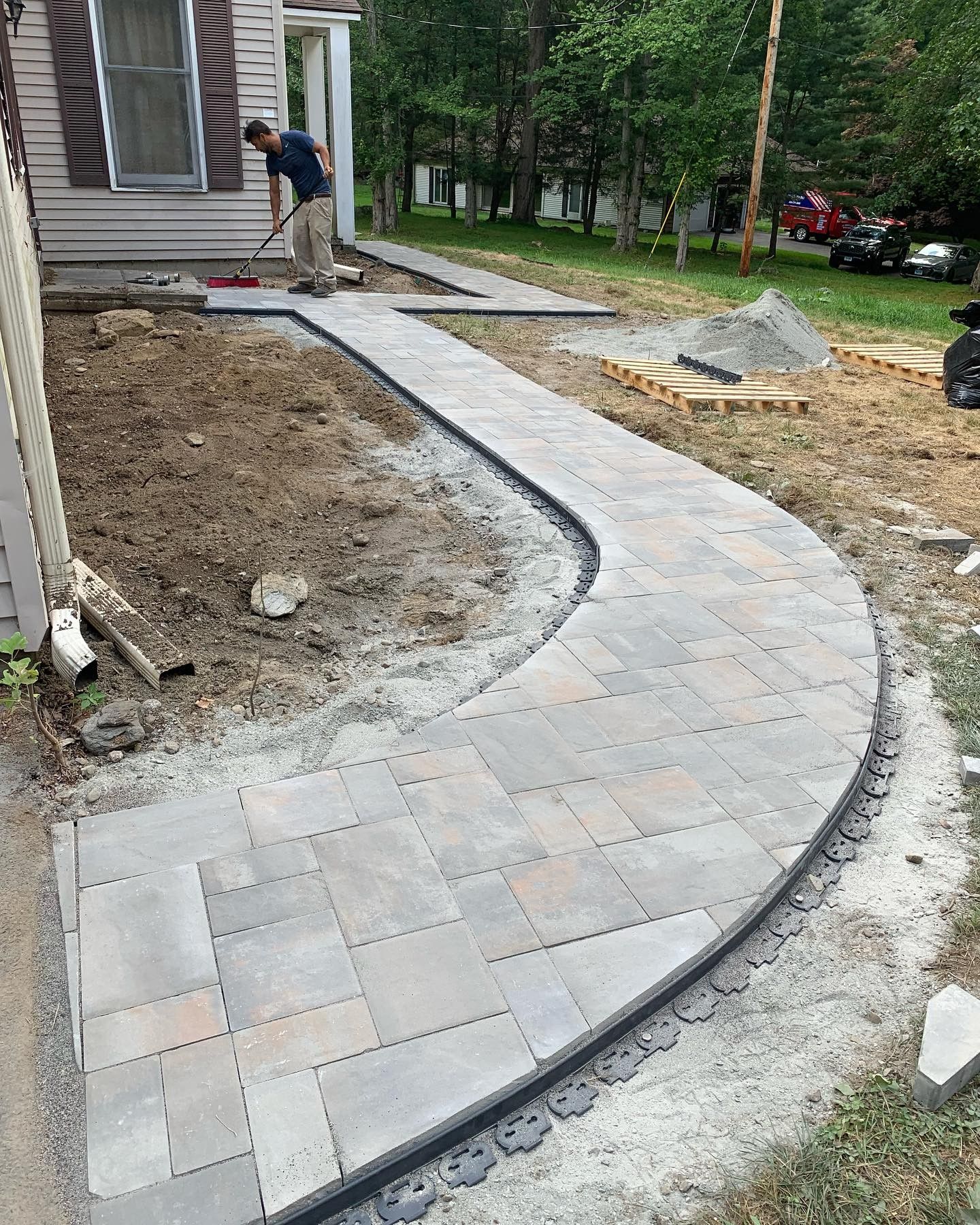 A man is working on a walkway in front of a house.