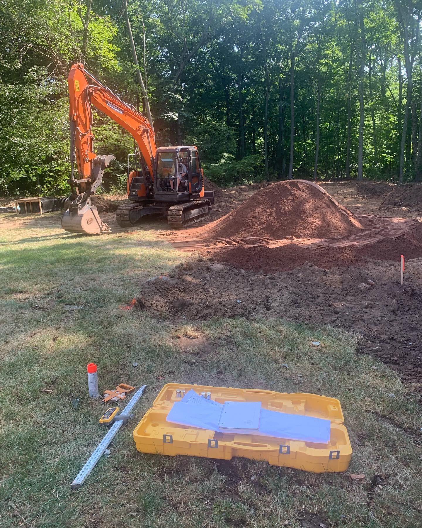 An excavator is digging a hole in the ground in a yard.