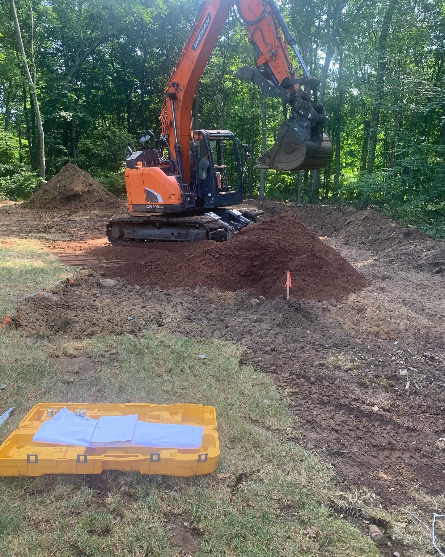 A large orange excavator is digging a hole in the dirt.